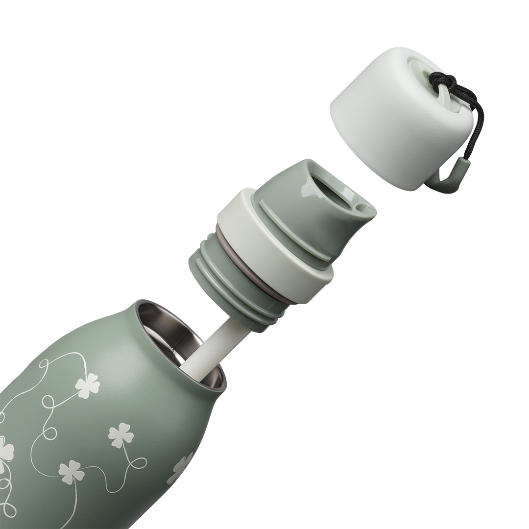 Owala FreeSip Twist 24oz in Clover Achiever, exploded view showing the sage green body with white clover pattern, sage twist cap removed exposing the white FreeSip spout, and the carry string